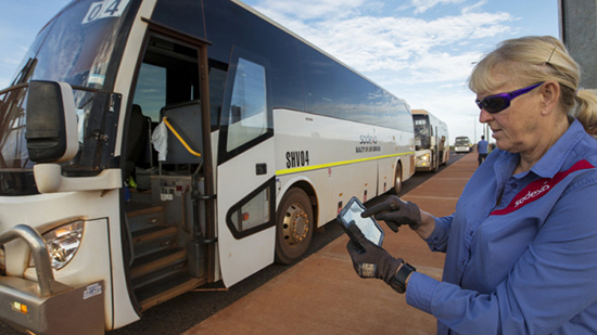Sodexo employee inputting information in to a tablet whilst standing in front of a coach