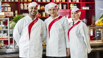 Trois chefs Sodexo posent devant un buffet de restaurant